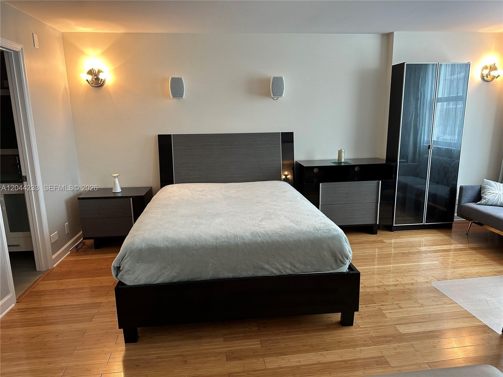 A bedroom features a dark wood bed frame, matching nightstand, dresser, and a tall wardrobe — 6039 Collins Ave # 1205, Miami Beach FL 33140, MIAMI BEACH, FL