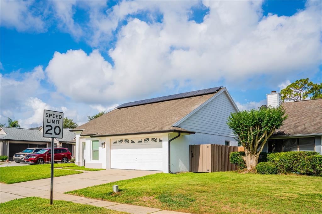 A residential house exterior with a white garage, solar panels, and a speed limit sign — 623 HOLBROOK CIRCLE, LAKE MARY, FL
