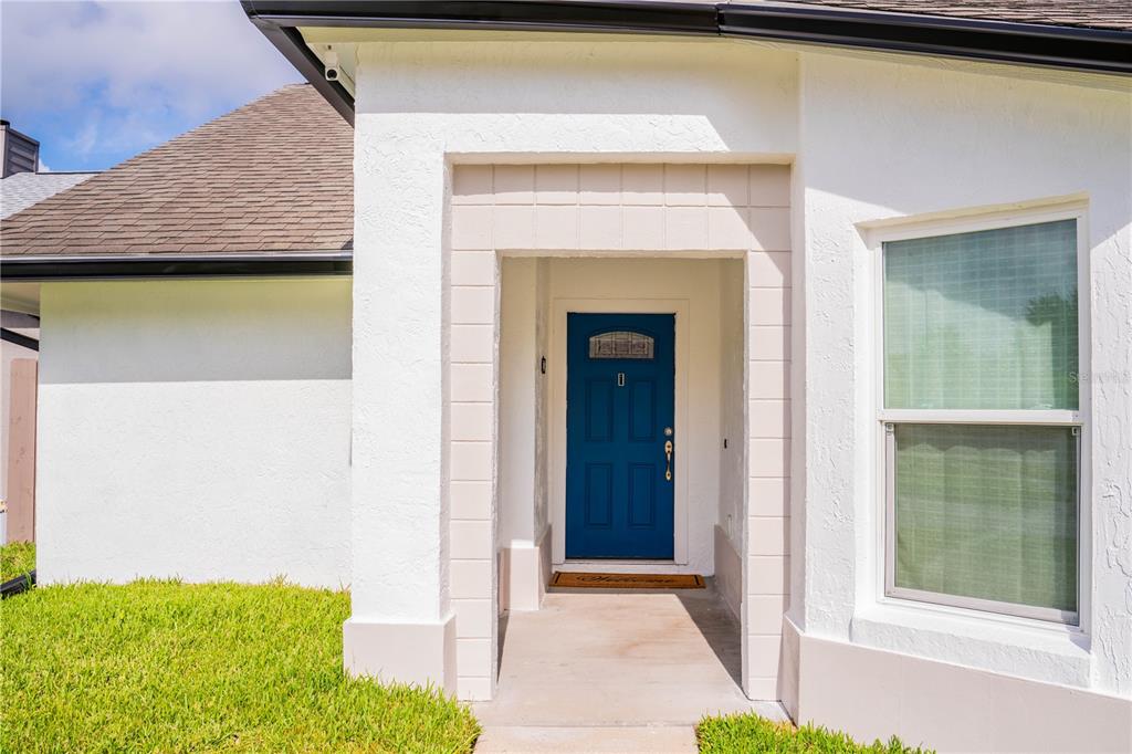 A white stucco house exterior features a blue front door and a small concrete entryway — 623 HOLBROOK CIRCLE, LAKE MARY, FL