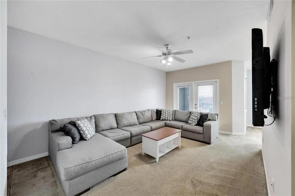 A spacious bedroom features beige carpeting, a ceiling fan, and decorative wall murals — 2010 E PALM AVENUE UNIT 14316, TAMPA, FL