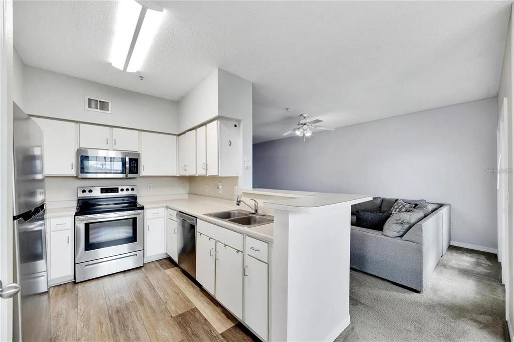 A living room features a sectional sofa, a coffee table, and a wall-mounted television — 2010 E PALM AVENUE UNIT 14316, TAMPA, FL