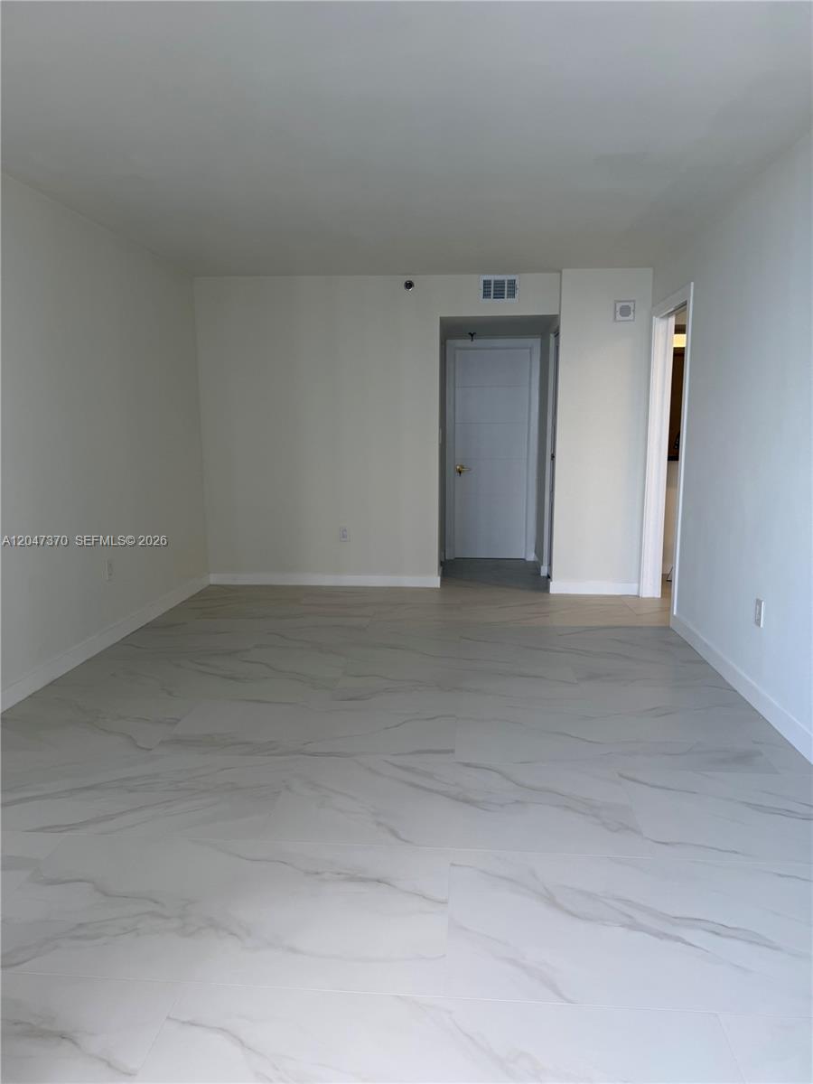 An empty room features white walls, large marble-patterned floor tiles, and two doorways — 555 NE 15th St # 23D, Miami FL 33132, MIAMI, FL