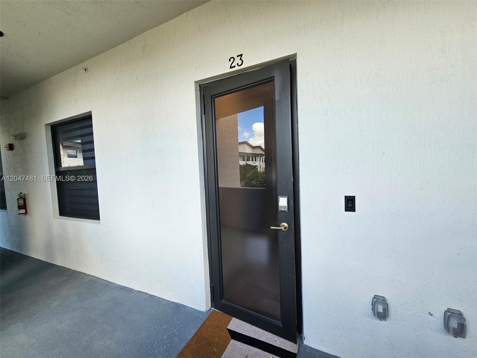 A black-framed glass door with number 23 sits on a white exterior wall — 8195 NW 104th Ave # 23, Doral FL 33178, DORAL, FL