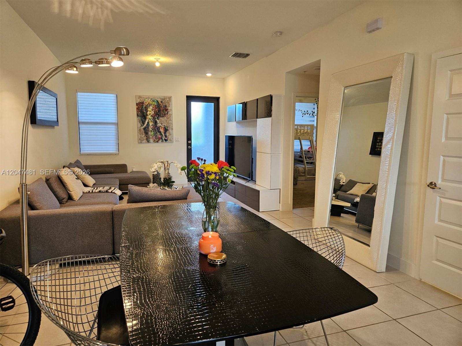 A dining area with a textured black table sits in front of a living room — 8195 NW 104th Ave # 23, Doral FL 33178, DORAL, FL