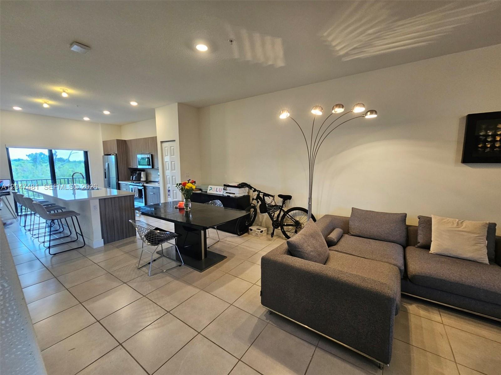 An open-concept living area features a kitchen with an island, dining table, and gray sofa — 8195 NW 104th Ave # 23, Doral FL 33178, DORAL, FL