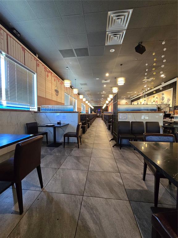 A restaurant interior features rows of tables, dark chairs, and marble-patterned partitions under pendant lights — 13605 SR 535 UNIT 102, ORLANDO, FL