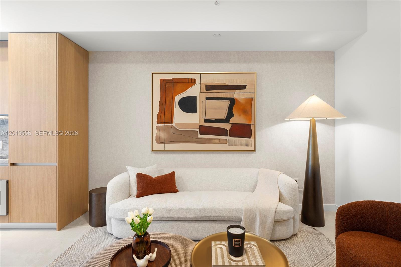 A modern living room features a white sofa, abstract wall art, and a floor lamp — 500 Alton Rd # 502, Miami Beach FL 33139, MIAMI BEACH, FL