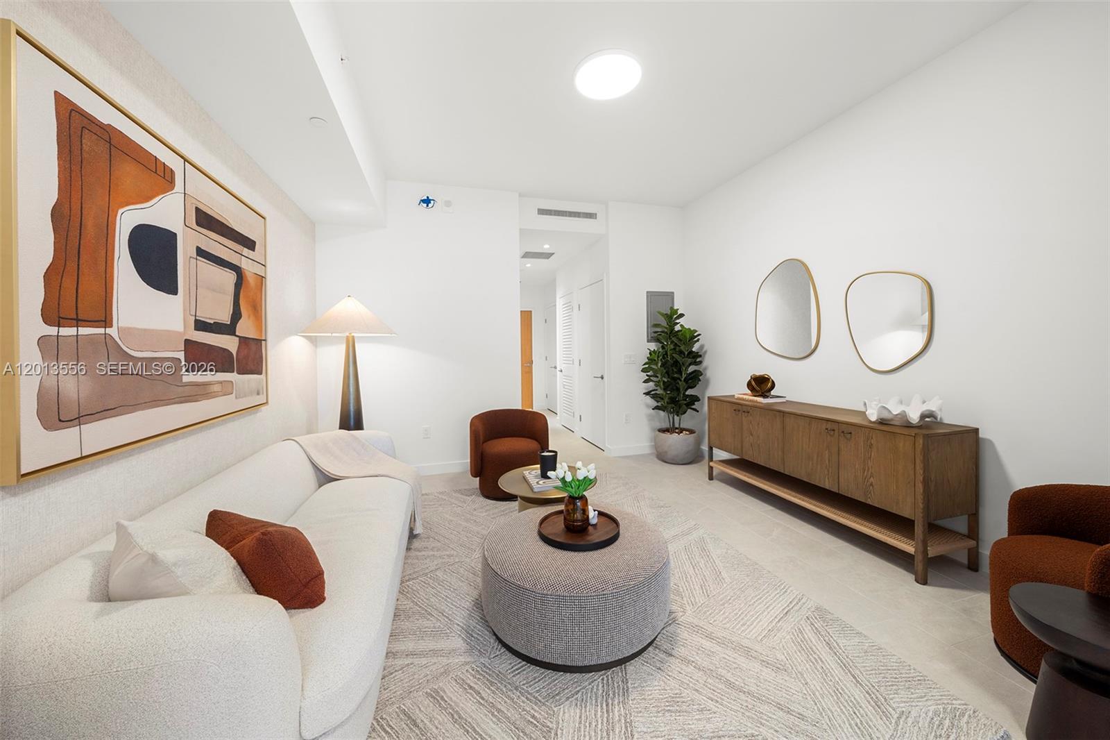 A modern living room features a white sofa, a round ottoman, and a wooden sideboard — 500 Alton Rd # 502, Miami Beach FL 33139, MIAMI BEACH, FL