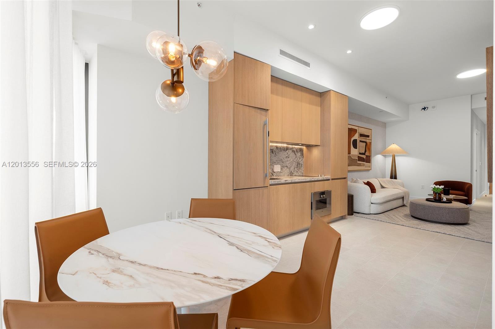 A dining area with a marble table and modern pendant light sits beside a kitchenette — 500 Alton Rd # 502, Miami Beach FL 33139, MIAMI BEACH, FL
