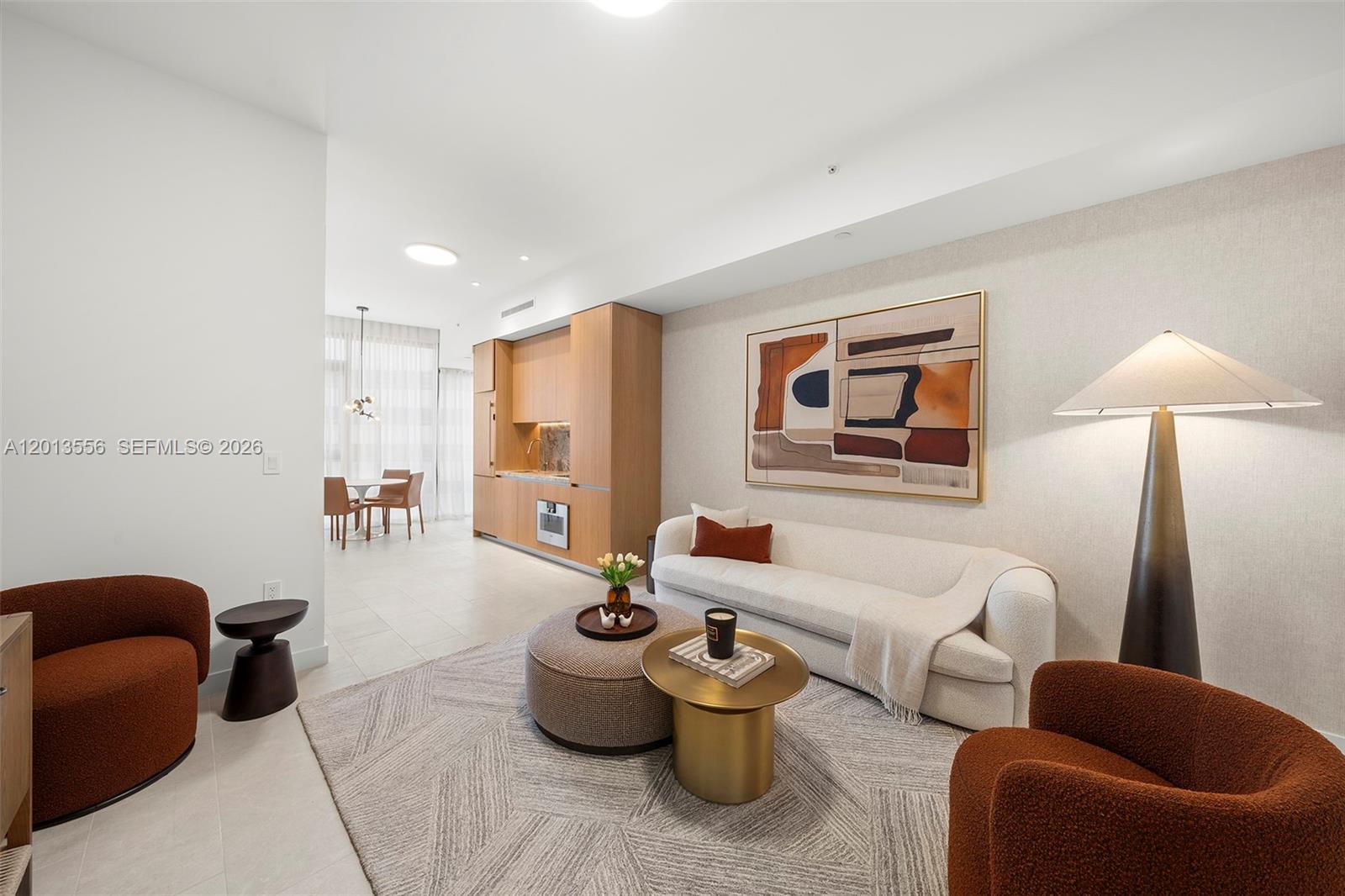 A modern living room features a cream sofa, two rust-colored chairs, and a kitchenette — 500 Alton Rd # 502, Miami Beach FL 33139, MIAMI BEACH, FL