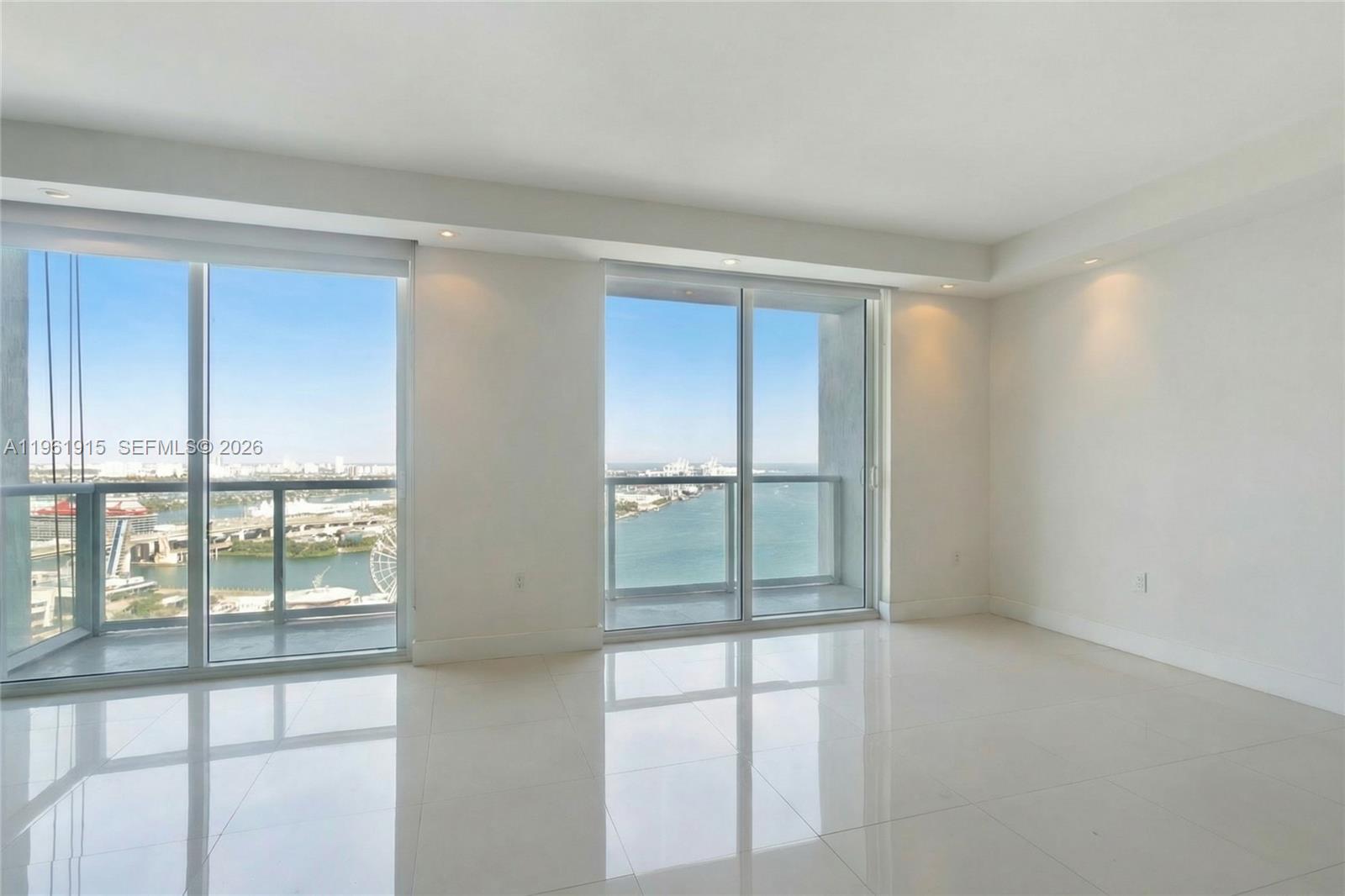 An empty room with white tile floors and two sliding glass doors overlooking the water — 253 NE 2nd St # 3105, Miami FL 33132, MIAMI, FL