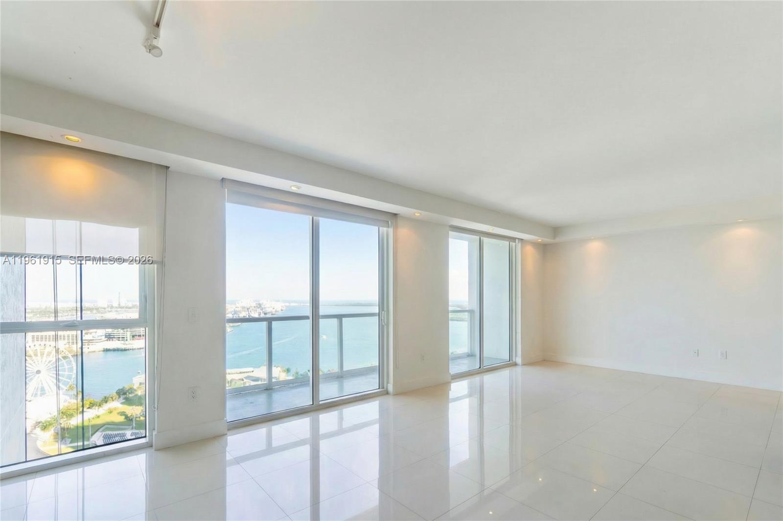 A bright, minimalist living room features white tile floors, recessed lighting, and floor-to-ceiling windows — 253 NE 2nd St # 3105, Miami FL 33132, MIAMI, FL