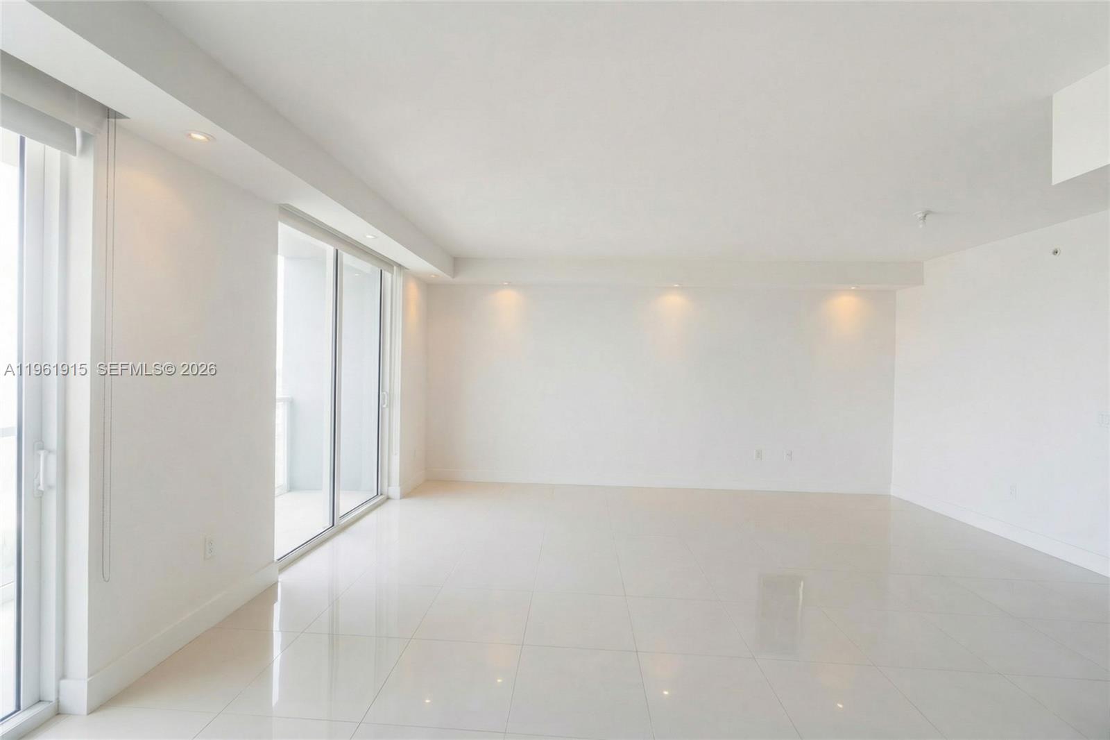 A bright, empty living room features white walls, glossy tile floors, and sliding glass doors — 253 NE 2nd St # 3105, Miami FL 33132, MIAMI, FL