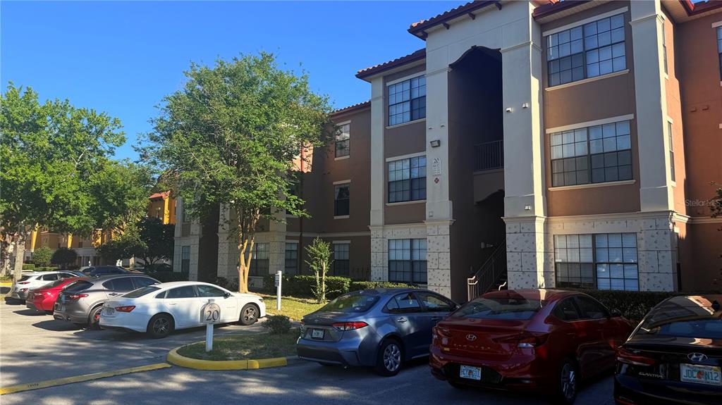 A multi-story apartment building exterior with a parking lot in the foreground — 6137 METROWEST BOULEVARD UNIT 307, ORLANDO, FL