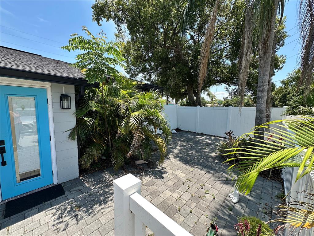 A paved patio area sits beside a house with a bright blue door and palm trees — 4521 EDGEWATER DRIVE UNIT 2, ORLANDO, FL