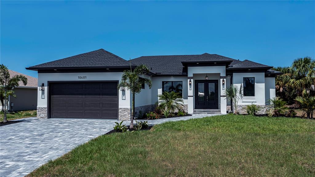 A modern single-story house features a dark garage, stone accents, and a paved driveway — 11 PINEHURST COURT, ROTONDA WEST, FL
