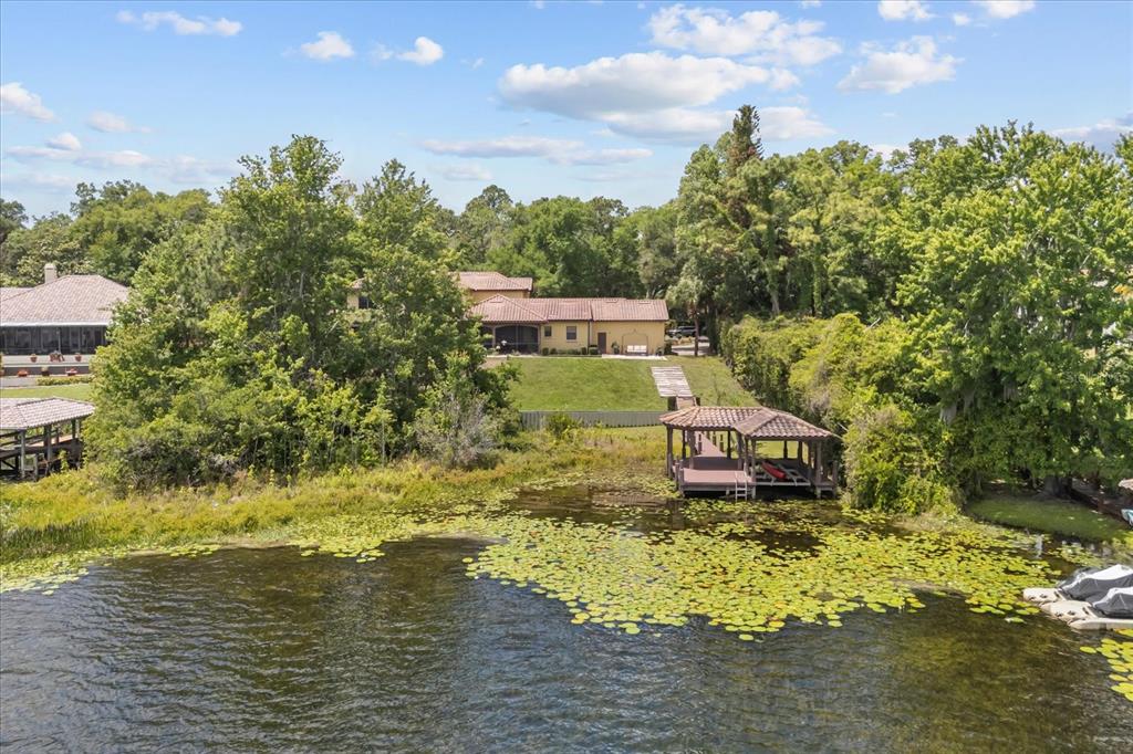 An aerial view of a house with a boat dock on a lily-covered lake — 1244 E LAKE COLONY DRIVE, MAITLAND, FL