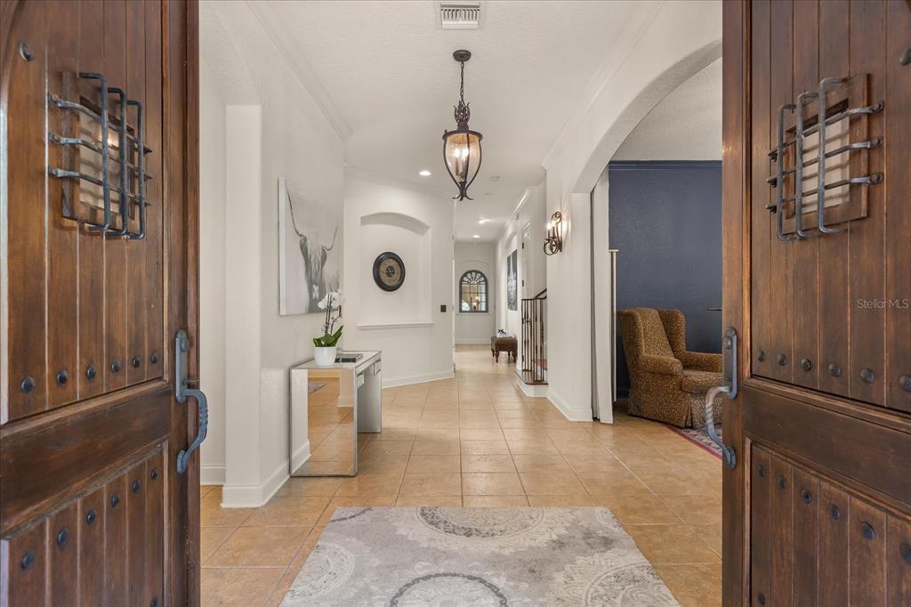 A tiled entryway features wooden double doors with iron grilles and a mirrored console table — 1244 E LAKE COLONY DRIVE, MAITLAND, FL