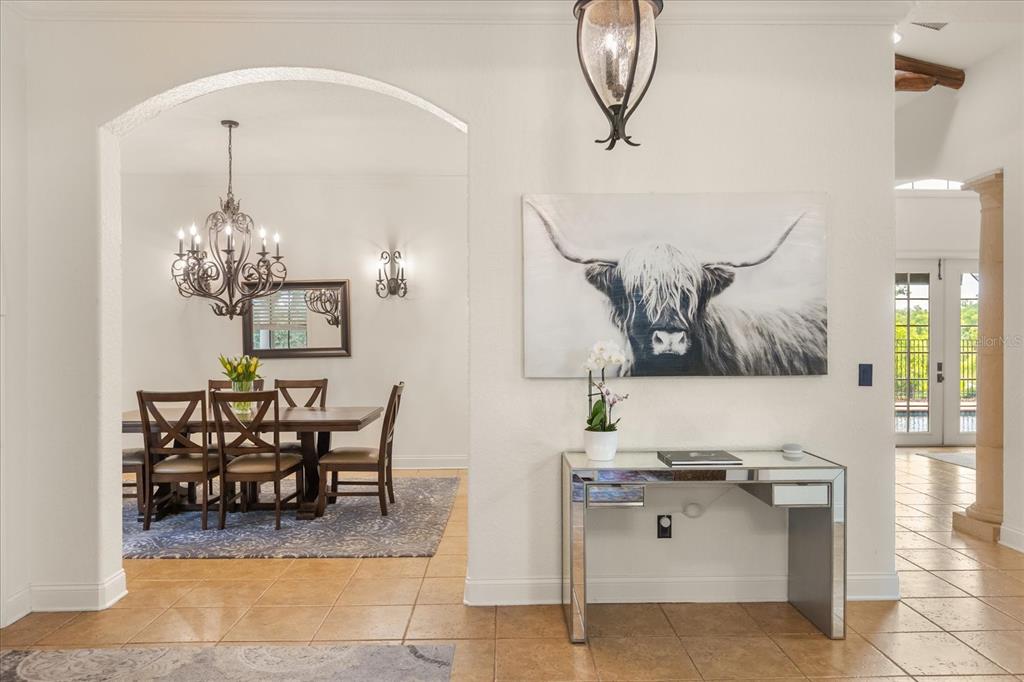 A dining room with a chandelier and a mirrored console table in the foreground — 1244 E LAKE COLONY DRIVE, MAITLAND, FL