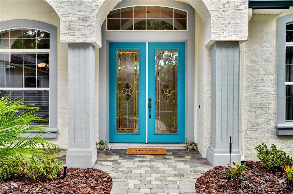 The exterior view shows a bright blue double front door with glass inserts and columns — 1435 DOLPH CIRCLE, ORMOND BEACH, FL