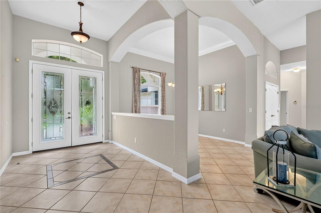 A bright foyer features tile flooring, a double-door entrance, and an arched wall partition — 1435 DOLPH CIRCLE, ORMOND BEACH, FL