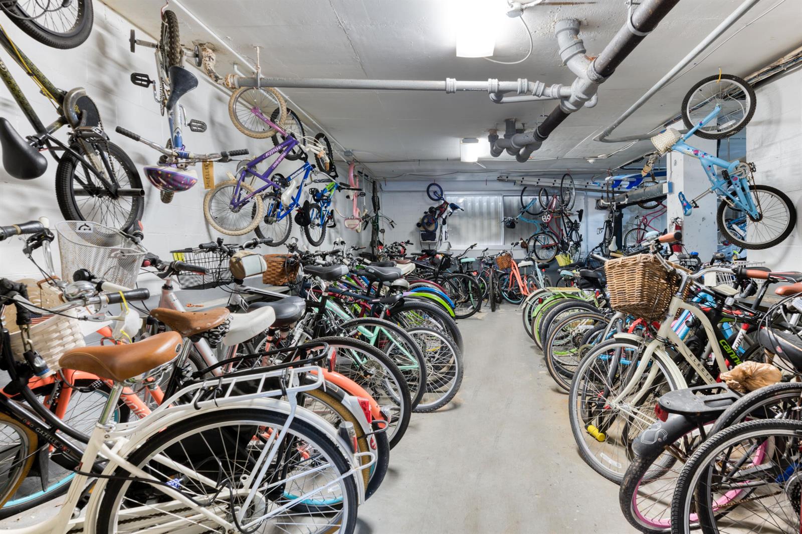 A basement storage room is filled with numerous bicycles hanging from the ceiling and floor — 170 N Ocean Boulevard # 303, Palm Beach FL 33480, PALM BEACH, FL