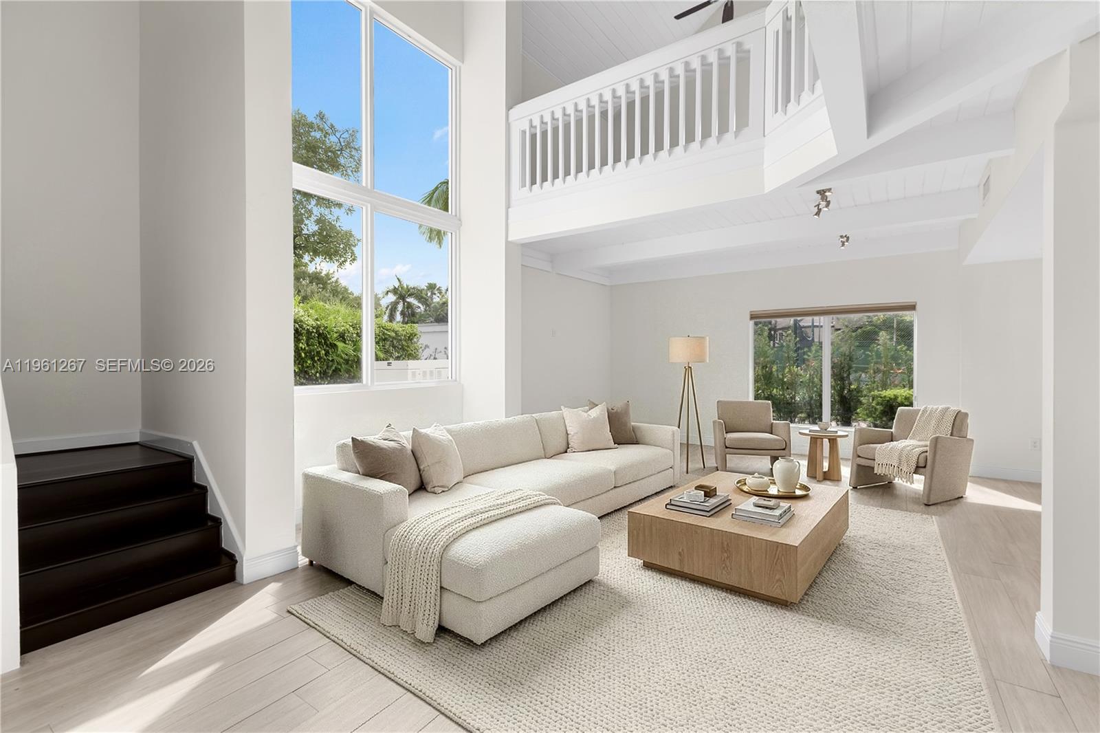 A bright living room features a high ceiling, large windows, a sectional sofa, and stairs — 20205 W Oak Haven Cir, Miami FL 33179, MIAMI, FL
