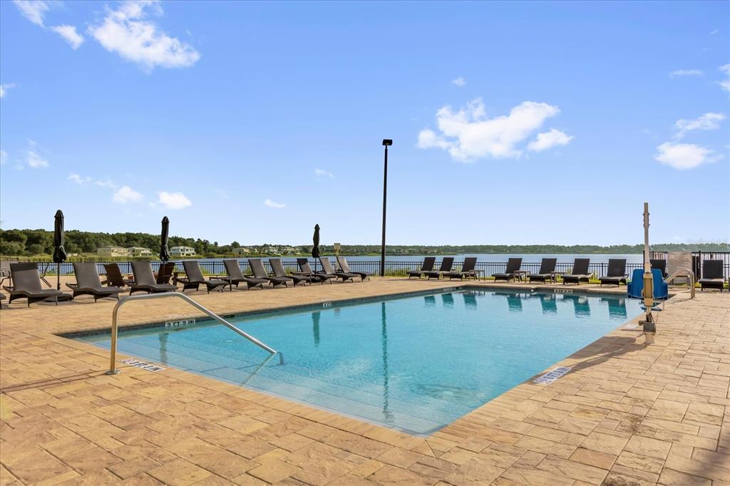 A swimming pool with lounge chairs on a patio overlooking a lake under a sky — 16300 COUNTY ROAD 455 UNIT 410, MONTVERDE, FL