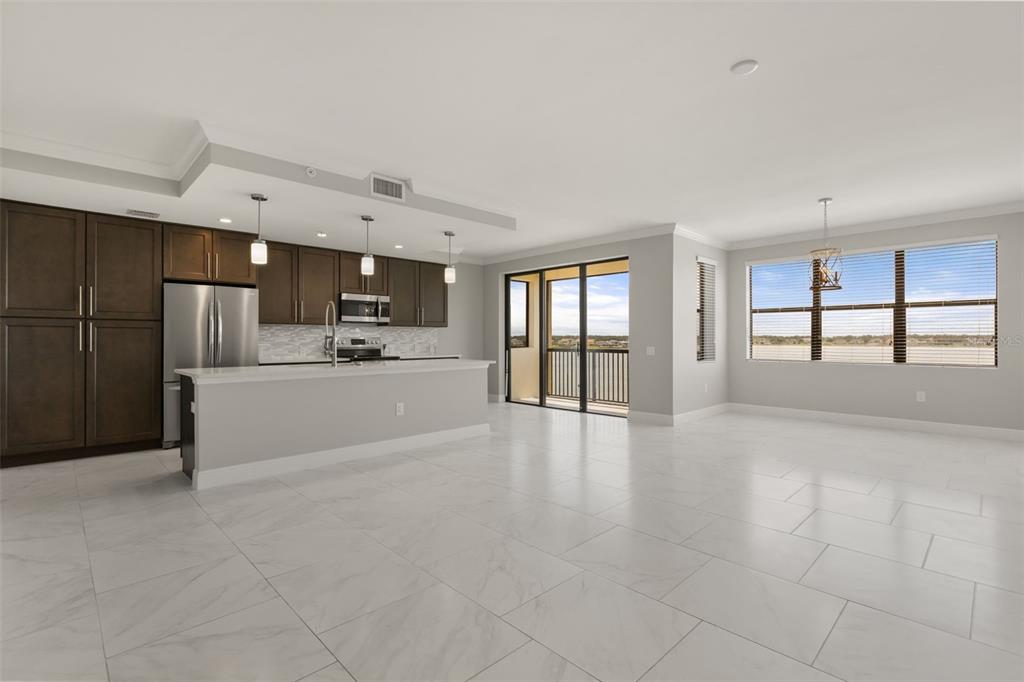An open-concept kitchen and living area featuring dark cabinetry, a breakfast bar, and tile flooring — 16300 COUNTY ROAD 455 UNIT 410, MONTVERDE, FL