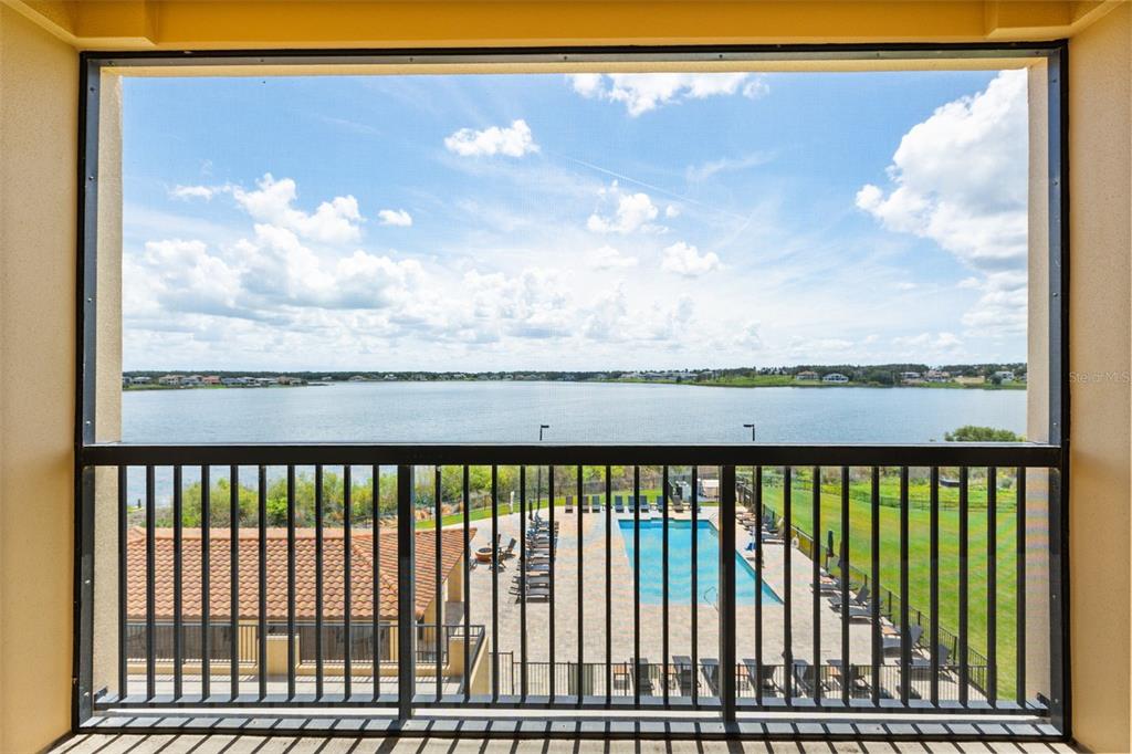 A balcony view overlooks a swimming pool, a grassy lawn, and a large lake — 16300 COUNTY ROAD 455 UNIT 410, MONTVERDE, FL