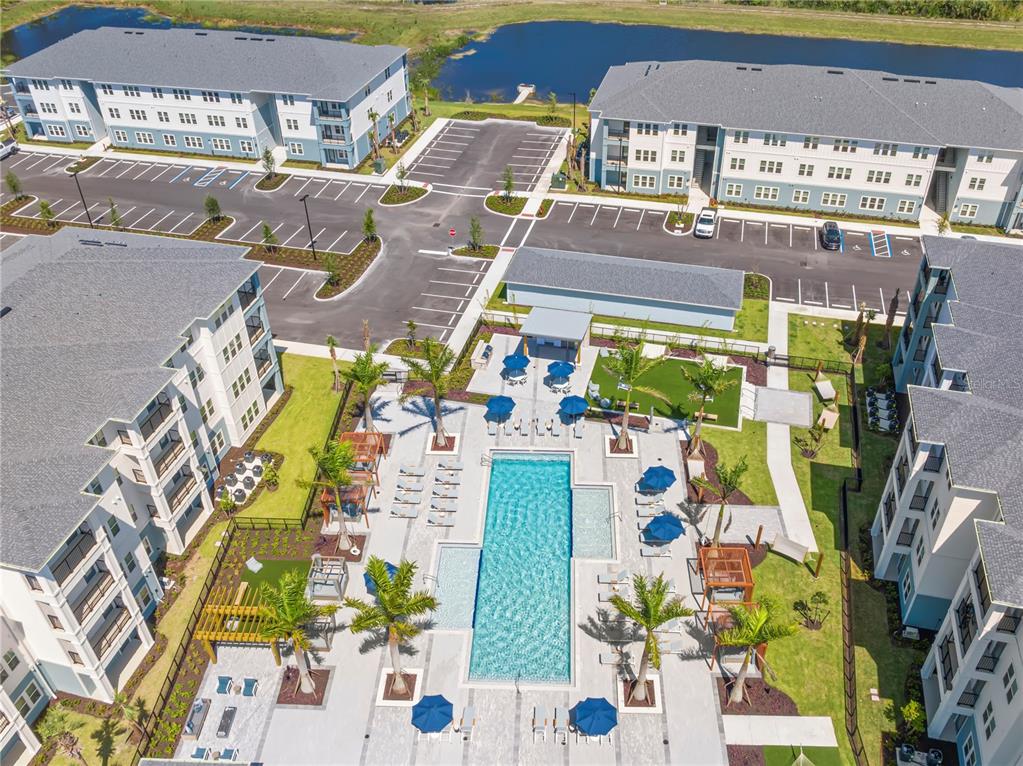 An aerial view shows an apartment complex with a central swimming pool and parking lots — 9720 BEAMING ROAD UNIT C1.2, VENICE, FL
