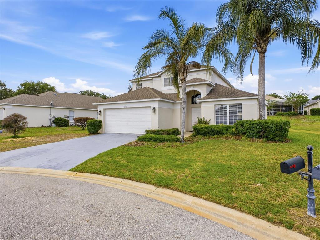 A two-story suburban house features a two-car garage, a concrete driveway, and palm trees — 1656 DUNES COURT, HAINES CITY, FL