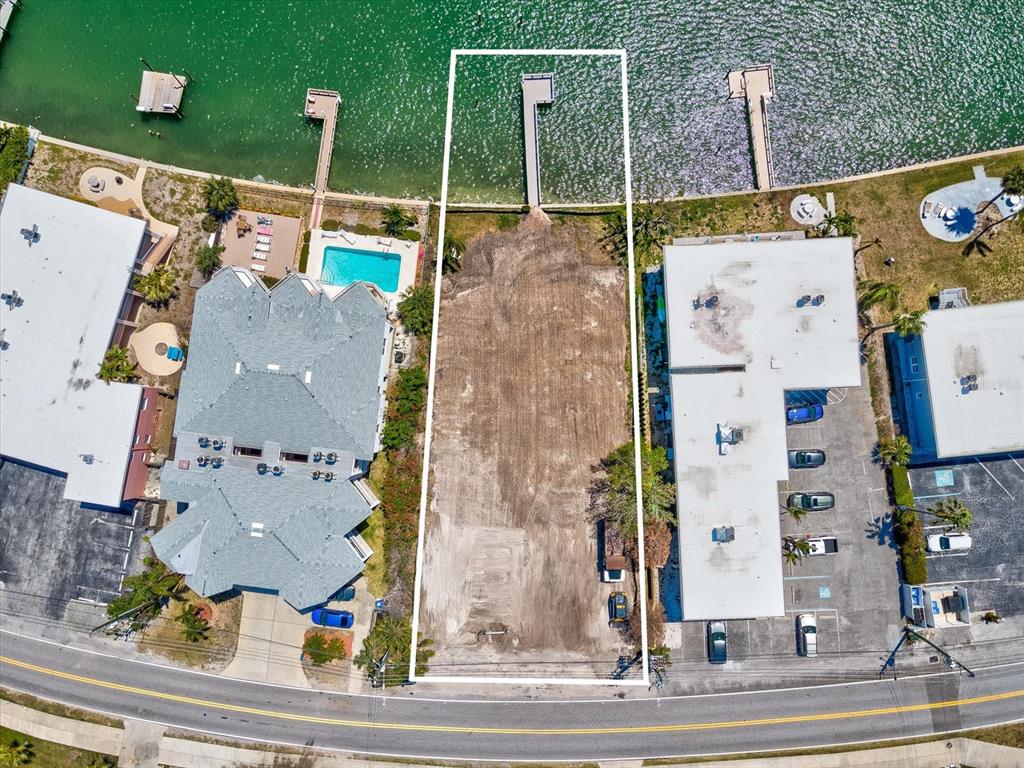 An aerial view shows a vacant, rectangular waterfront lot situated between two existing buildings — 141 104TH AVENUE, TREASURE ISLAND, FL