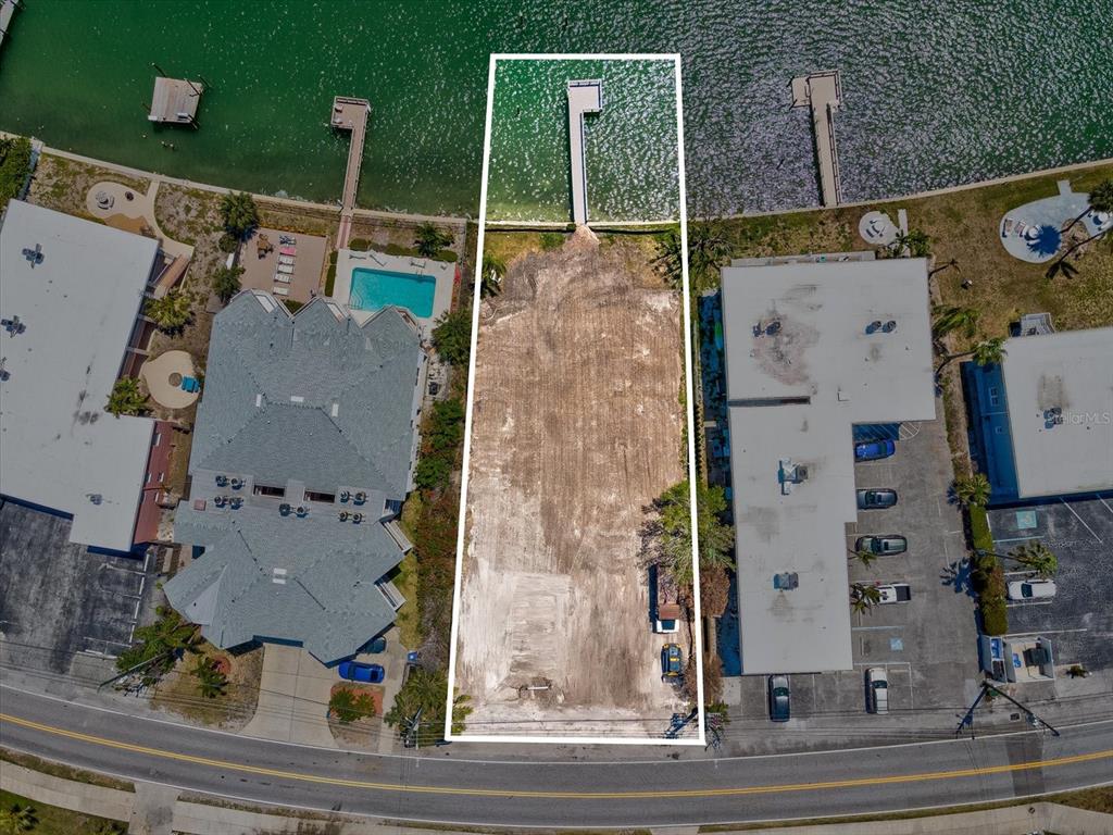 An aerial view shows a vacant, rectangular waterfront lot situated between two existing buildings — 141 104TH AVENUE, TREASURE ISLAND, FL