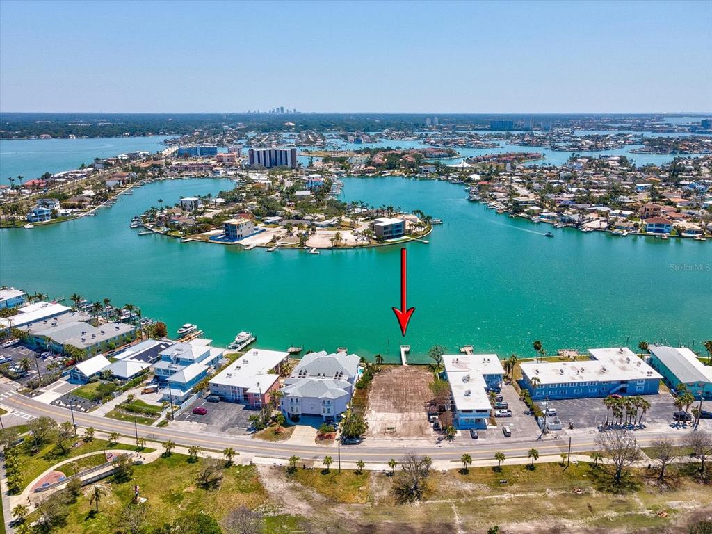An aerial view shows a vacant waterfront lot situated between two multi-story buildings — 141 104TH AVENUE, TREASURE ISLAND, FL