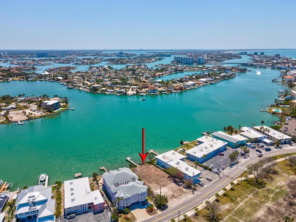 An aerial view shows a vacant waterfront lot situated between two multi-story residential buildings — 141 104TH AVENUE, TREASURE ISLAND, FL