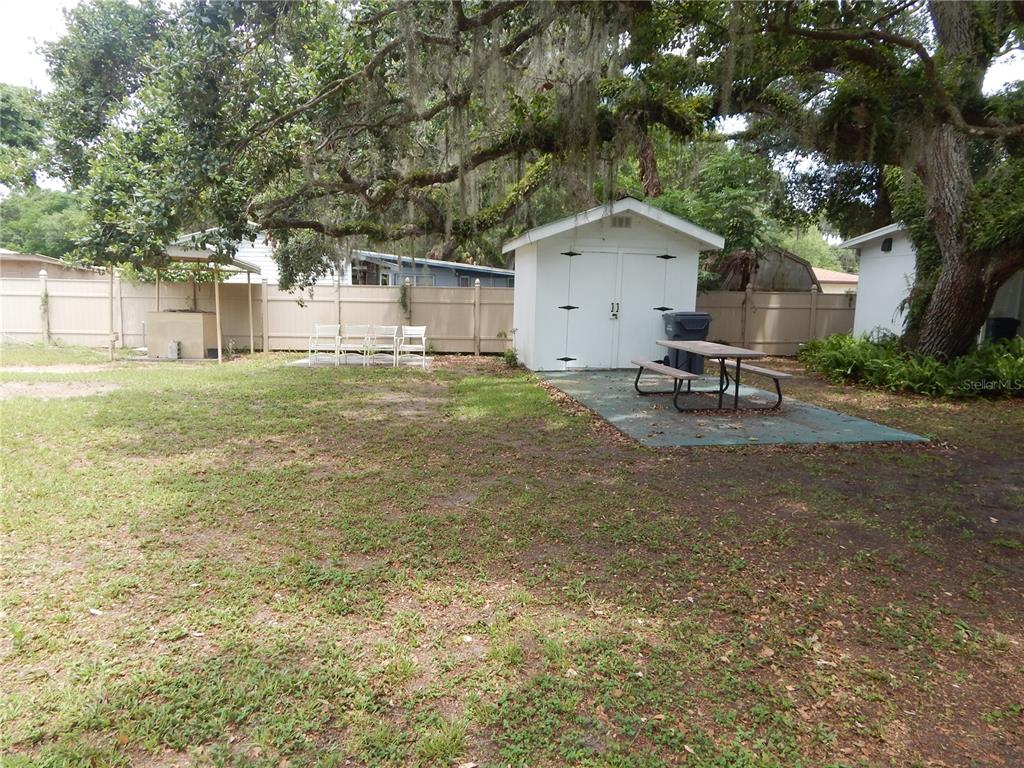 A backyard features a white storage shed, a picnic table, and a patio area — 21 ANCHOR INN ROAD, LAKE WALES, FL
