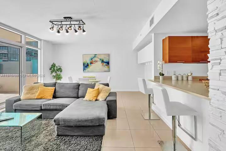 A living room with a gray sectional sofa, a glass coffee table, and a kitchen bar — 3250 NE 1st Ave # 501, Miami FL 33137, MIAMI, FL