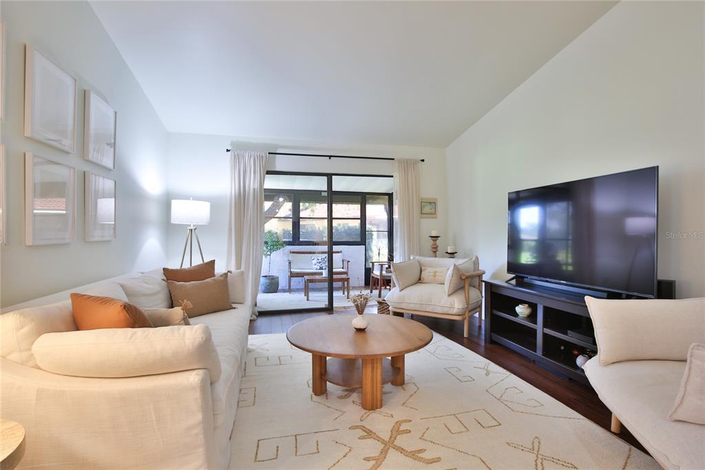 A living room features a white sofa, a round wooden coffee table, and a television — 1411 57TH STREET W UNIT 1411, BRADENTON, FL