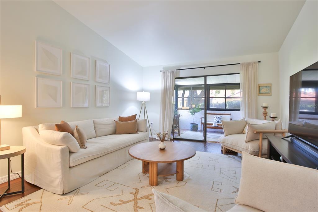 A living room features a white sofa, a round wooden coffee table, and sliding glass doors — 1411 57TH STREET W UNIT 1411, BRADENTON, FL