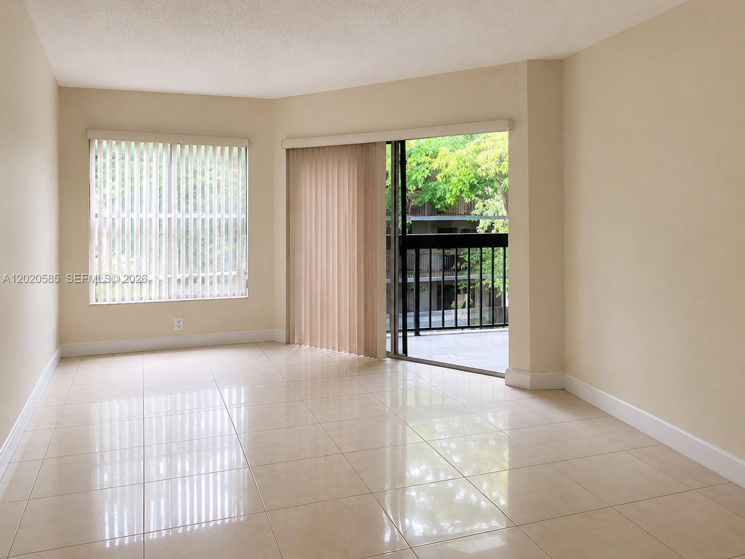 An empty room features beige tile flooring, a large window, and a sliding glass door — 13255 SW 88 LN, Kendall FL 33186, KENDALL, FL