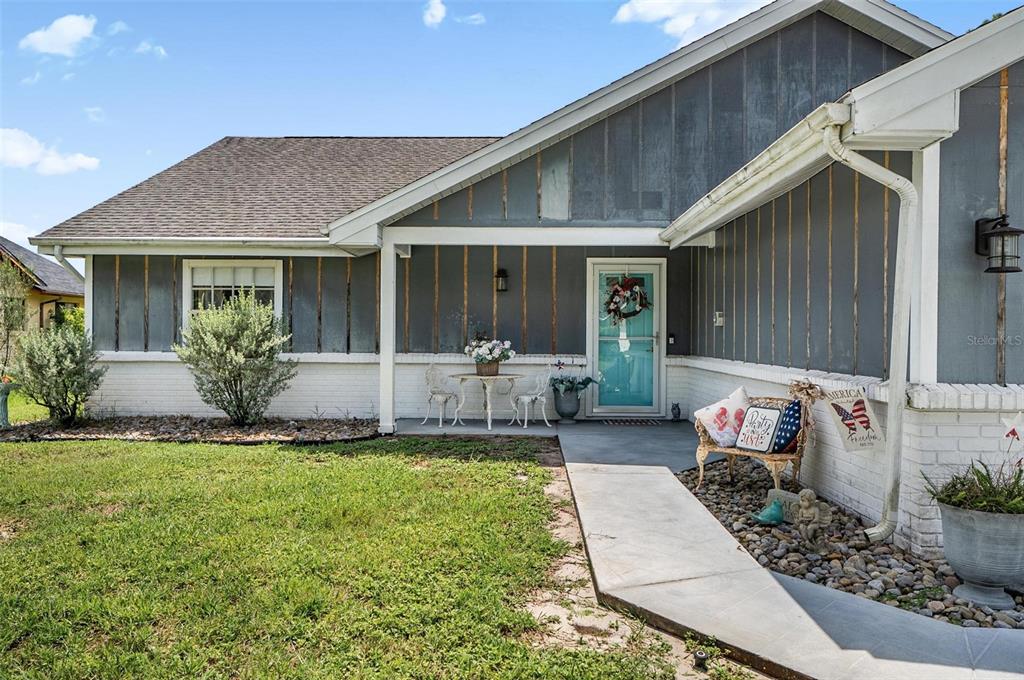 A gray house with white brick accents features a covered porch and a turquoise door — 186 WESTHAMPTON DRIVE, PALM COAST, FL