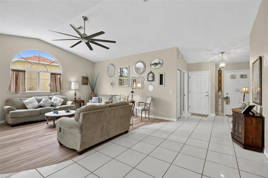 A living room features a vaulted ceiling, a large arched window, and wood-look flooring — 186 WESTHAMPTON DRIVE, PALM COAST, FL