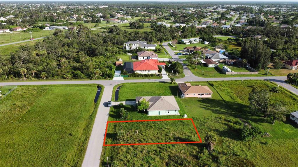 An aerial view shows a vacant rectangular lot outlined in red next to a house — HACIENDA ST, NORTH PORT, FL