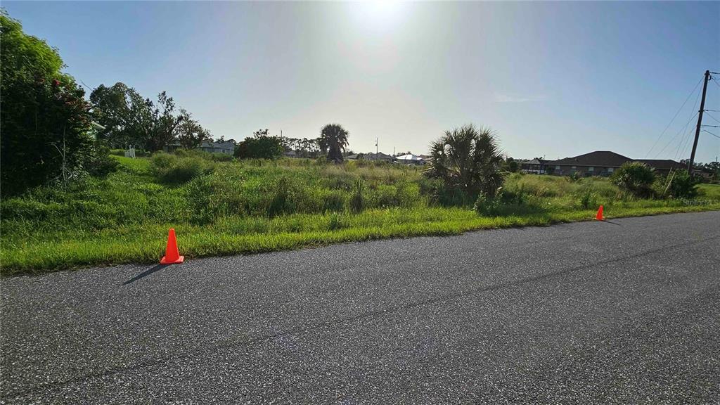 A vacant, grassy lot sits along a paved road with two orange traffic cones — HACIENDA ST, NORTH PORT, FL