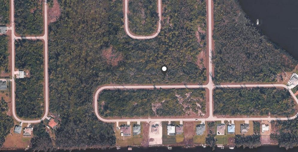 An aerial view of a vacant residential lot surrounded by wooded areas and nearby houses — 16856 LIGGETT CIRCLE, PORT CHARLOTTE, FL