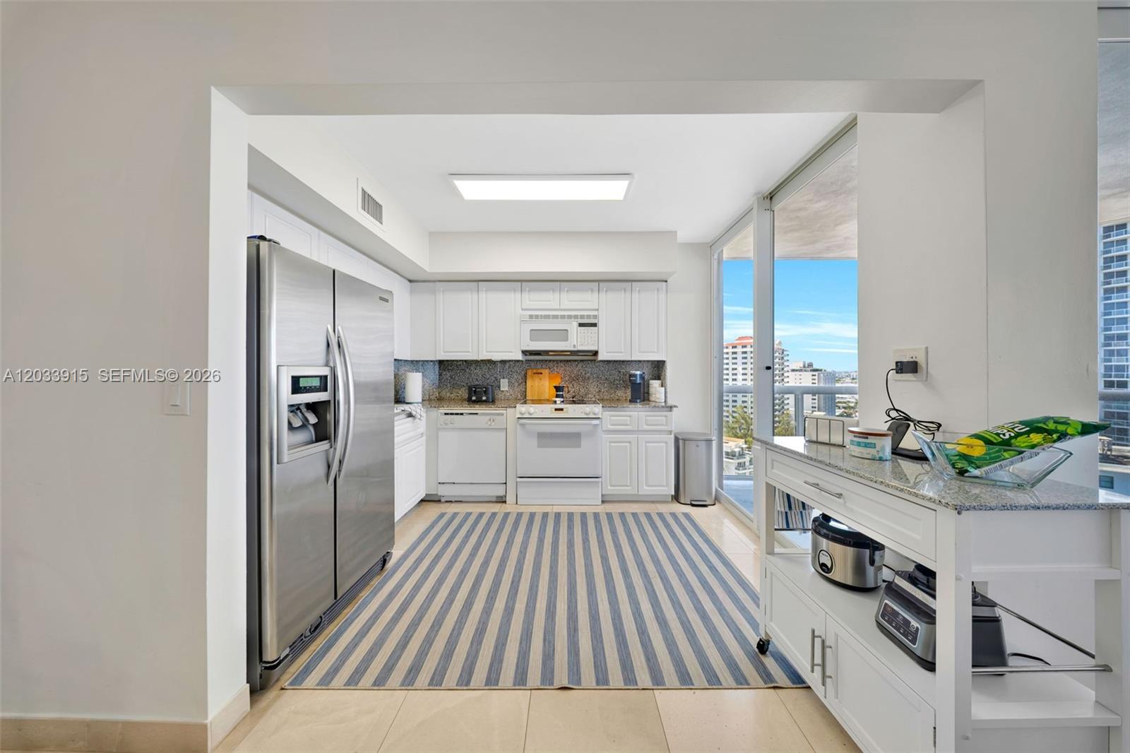 A kitchen features white cabinetry, stainless steel appliances, a striped rug, and a balcony view — 6301 Collins Ave # 1708, Miami Beach FL 33141, MIAMI BEACH, FL