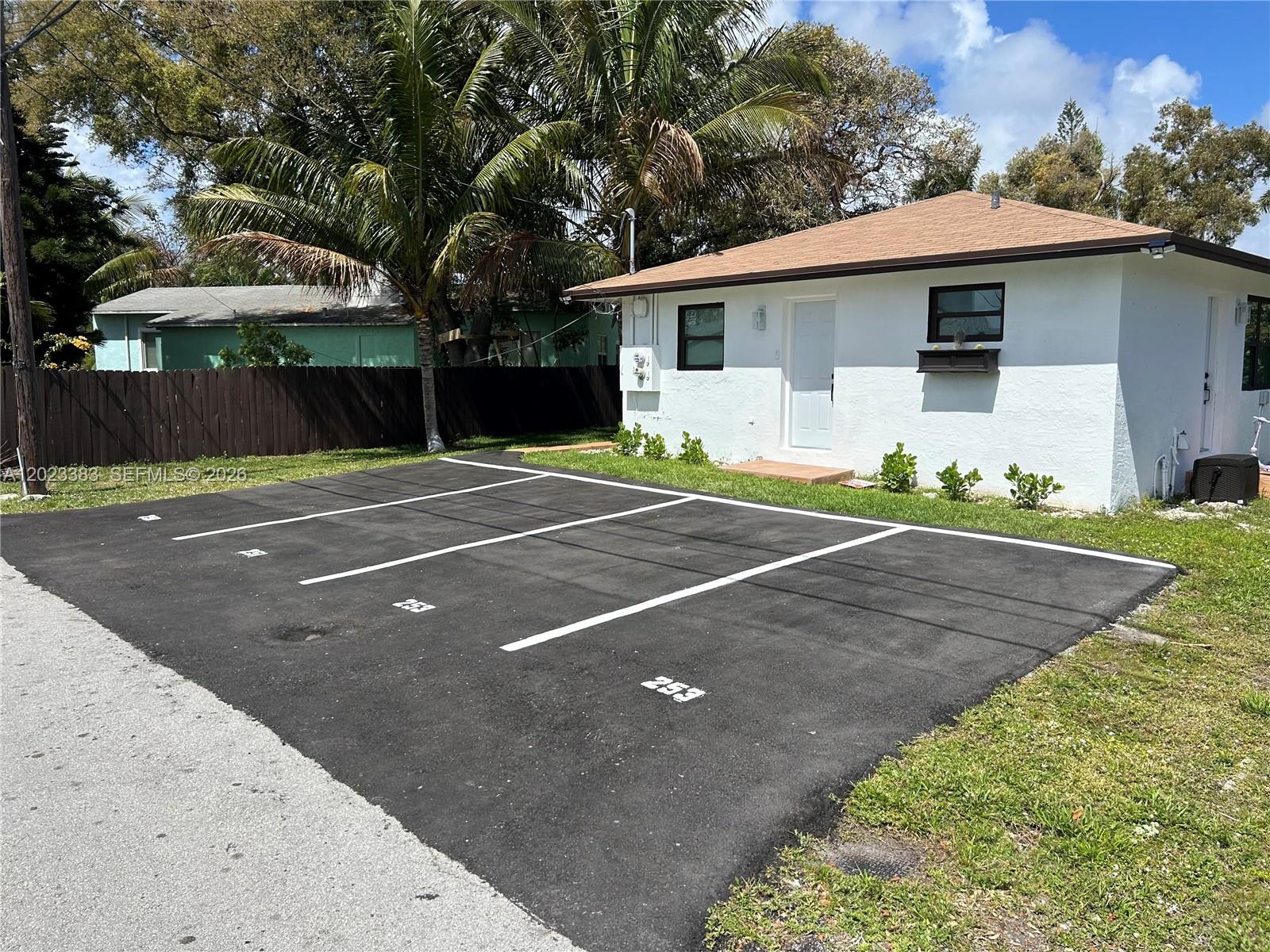 A white house with a brown roof sits behind a paved parking lot with numbered spaces — 251-253 SW 11th St, Dania Beach FL 33004, DANIA BEACH, FL