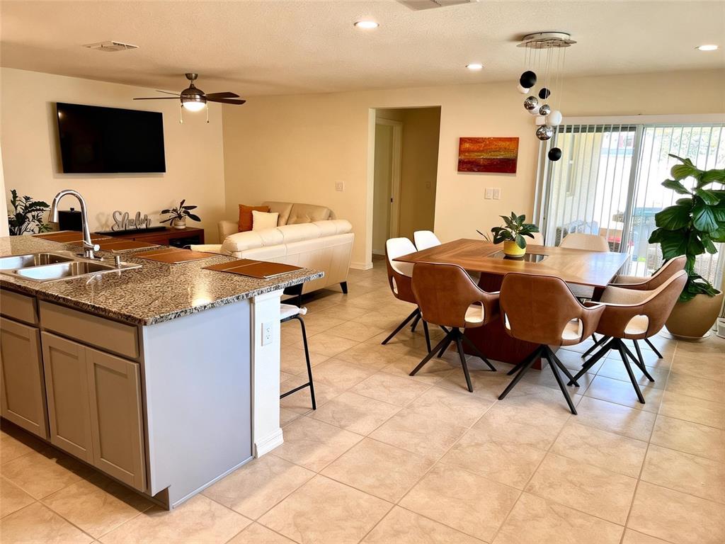 An open-concept kitchen, dining area, and living room feature tile floors and granite countertops — 2727 MEADOW STREAM WAY, CLERMONT, FL