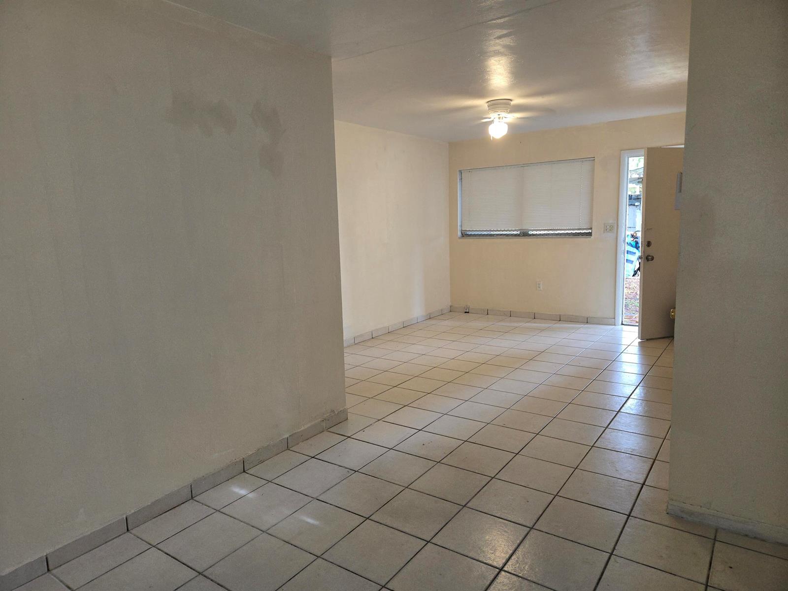 An empty room with white walls, light-colored tile flooring, a ceiling fan, and an entryway — 1560 NE 111th Street # 3, Miami FL 33161, MIAMI, FL